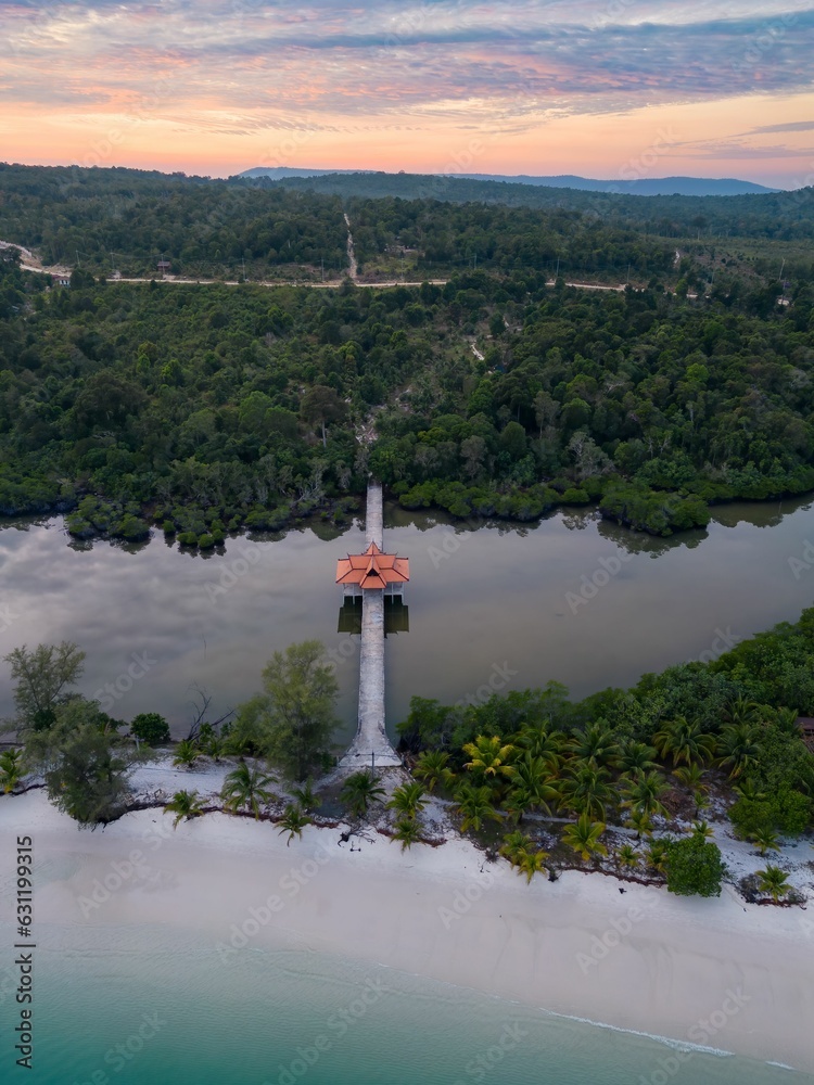 Aerial view of Koh Rong beach surrounded by dense trees during sunset