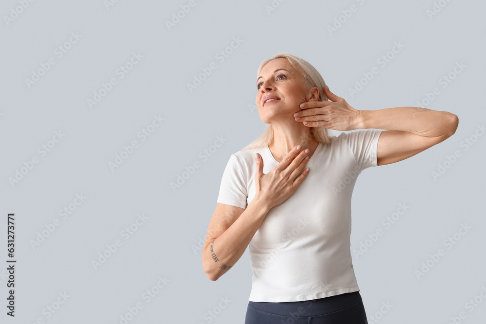 Mature woman doing face building exercise on light background