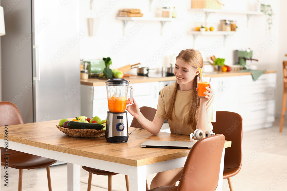 Young woman with healthy smoothie and blender in kitchen