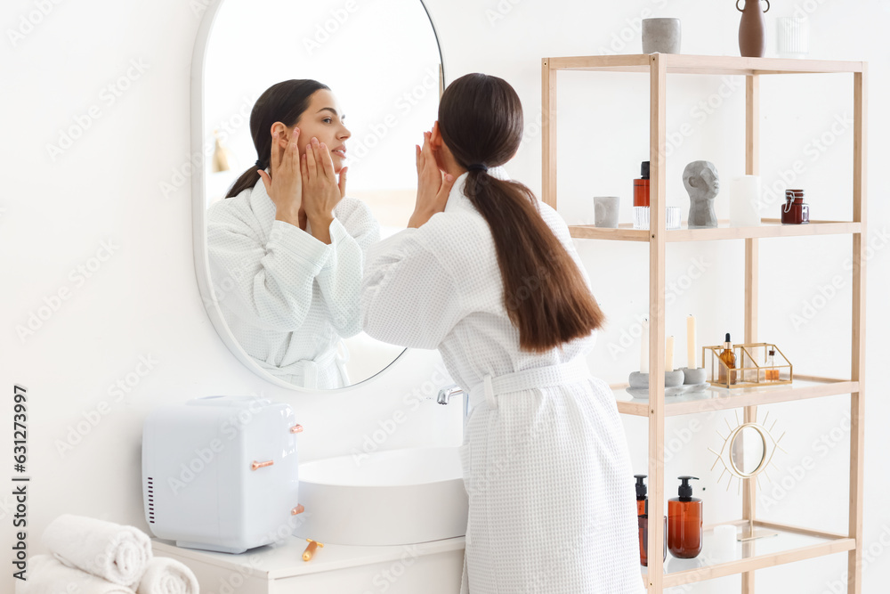 Young woman doing face building exercise near mirror in bathroom