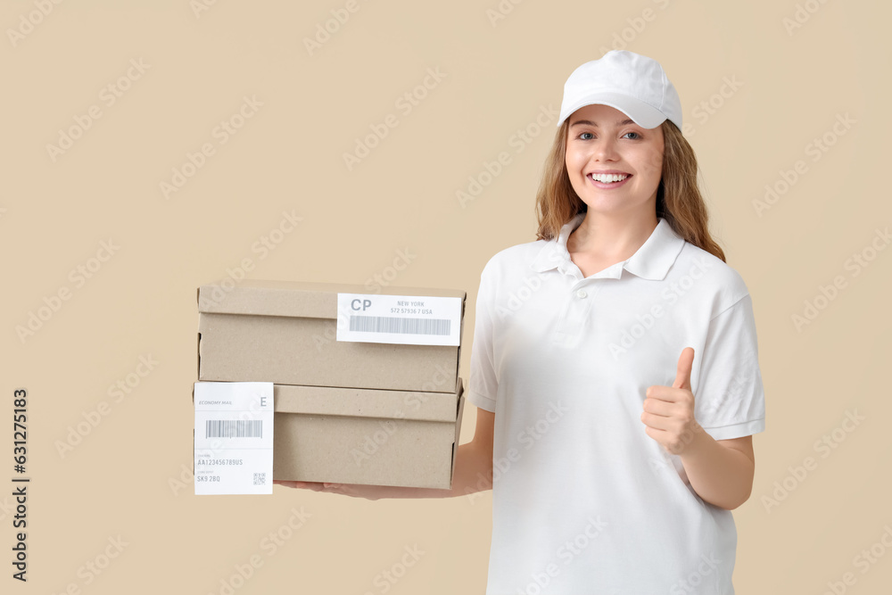 Female courier with parcels showing thumb-up on beige background