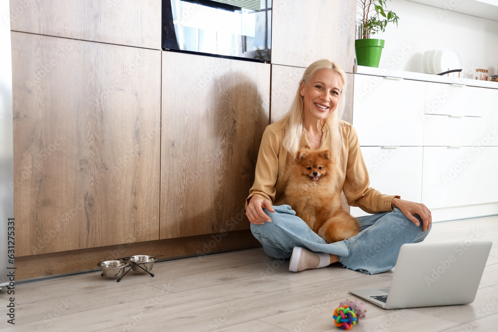 Mature woman with Pomeranian dog in kitchen