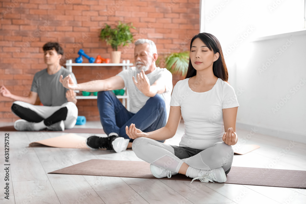 Group of sporty people meditating in gym