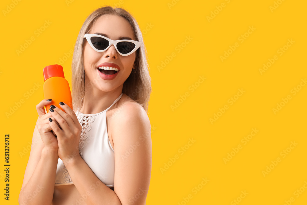 Young woman with sunscreen cream on yellow background