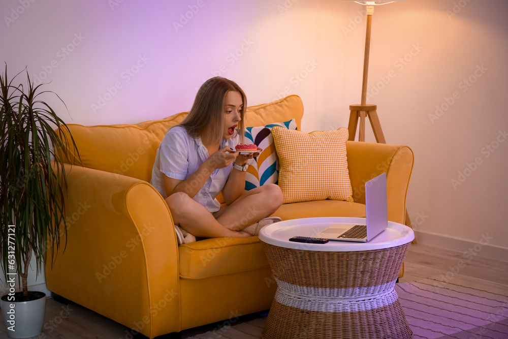 Young woman eating tasty doughnut at night