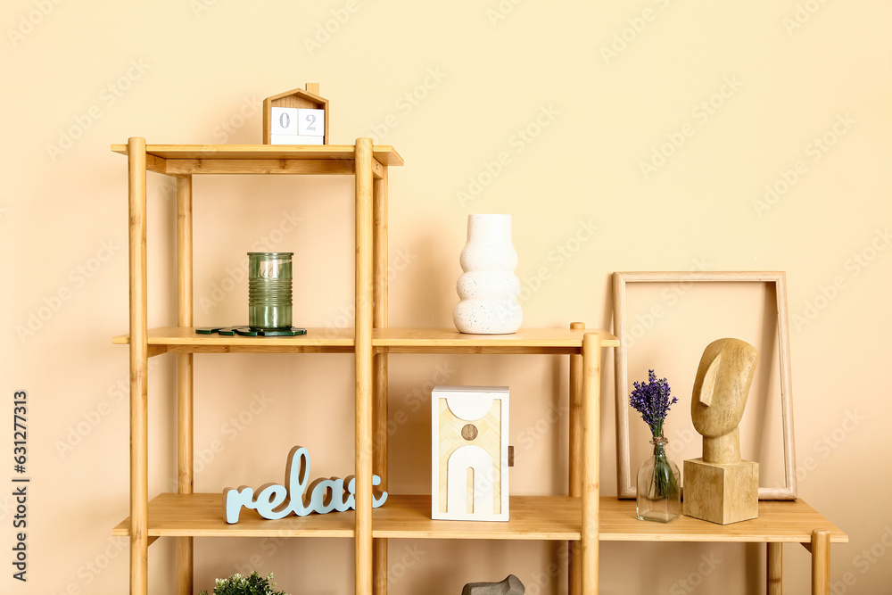 Shelving unit with stylish decor and beautiful lavender flowers near beige wall in room