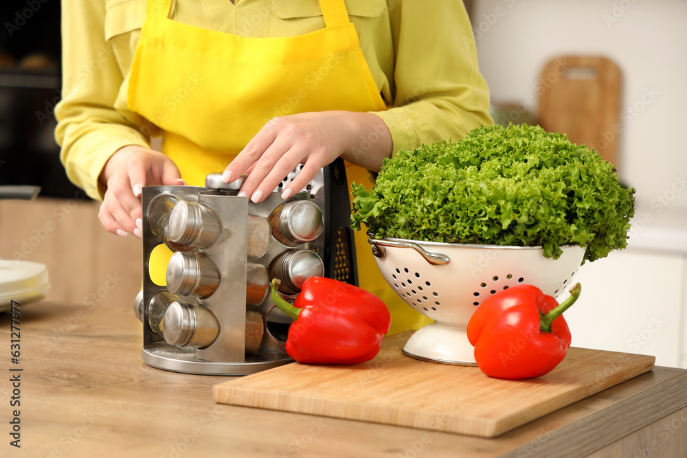 Young woman with spices cooking in kitchen, closeup