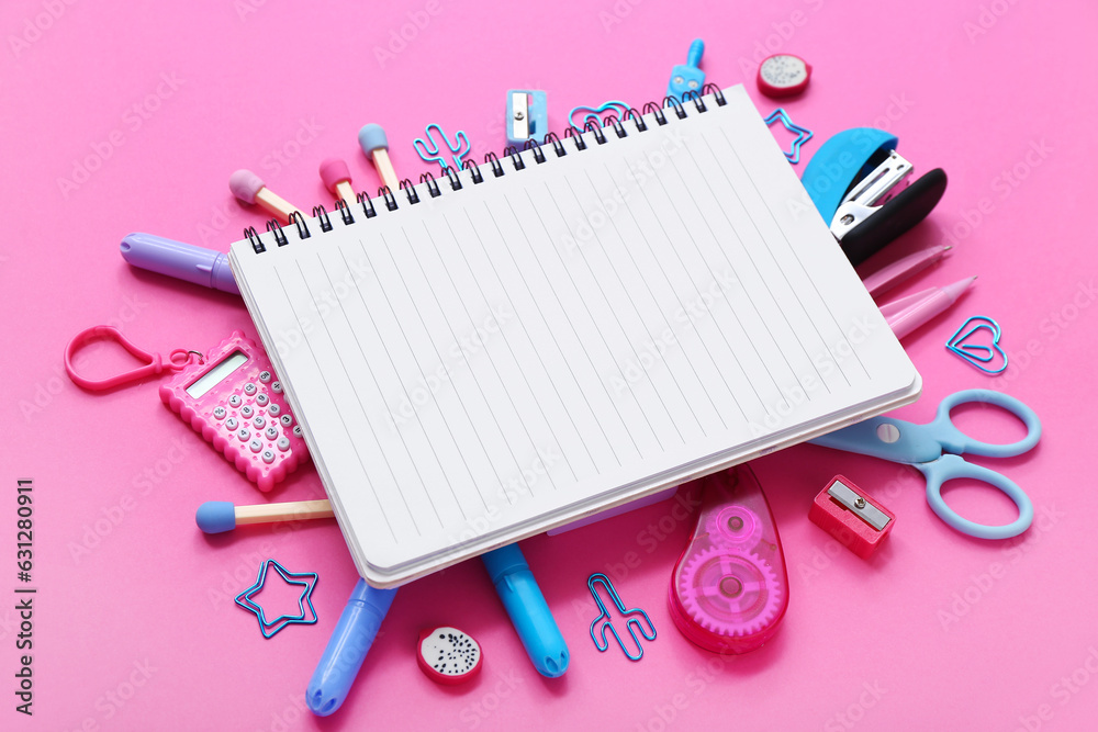 Notebook with different stationery supplies on pink background