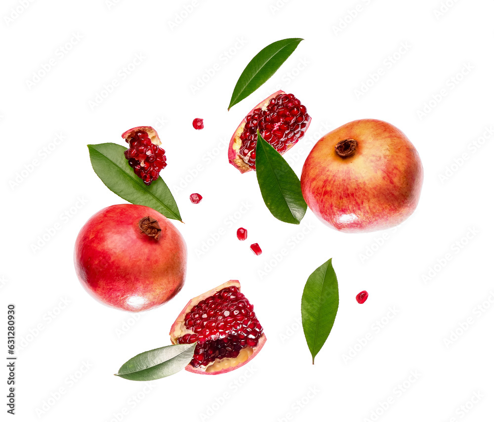 Flying fresh pomegranates with seeds and leaves on white background