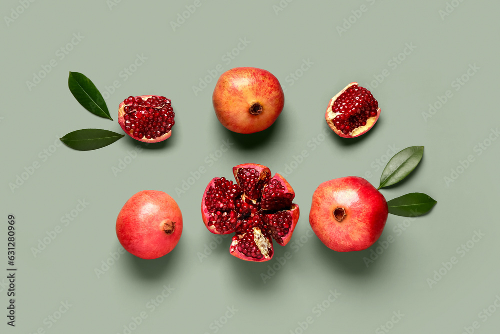 Fresh pomegranates and leaves on green background