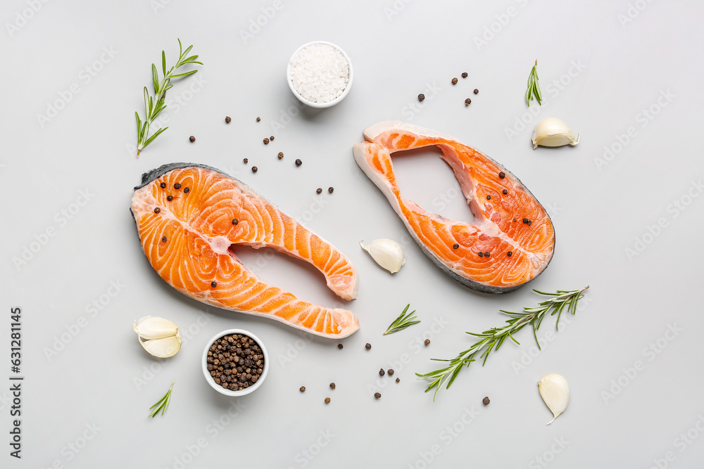 Raw salmon steaks and different spices on grey background