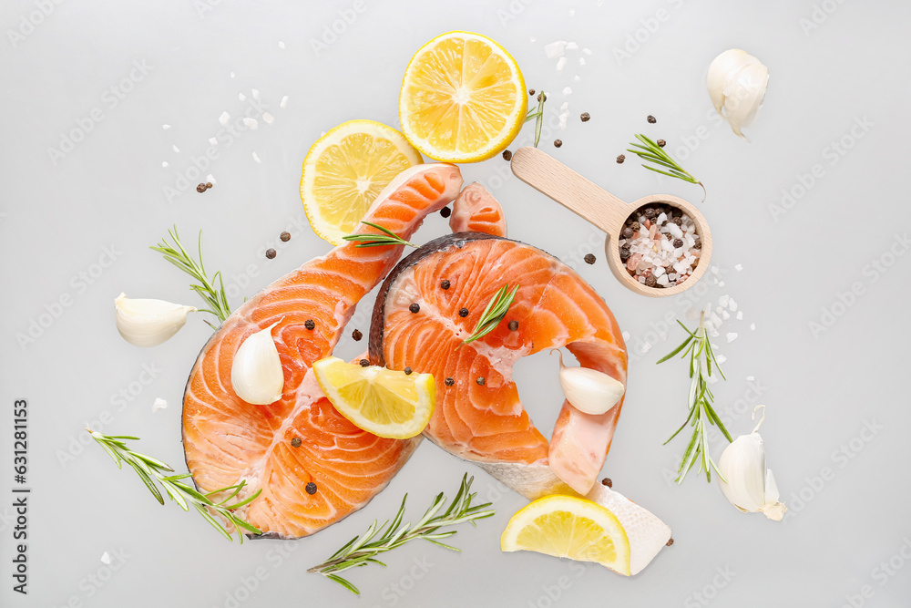 Flying raw salmon steaks and different spices on grey background