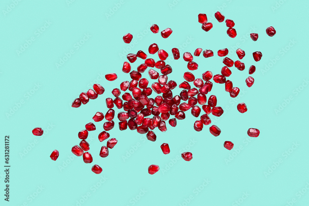 Flying fresh pomegranate seeds on turquoise background