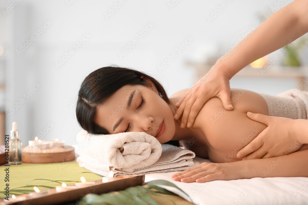 Pretty young Asian woman having massage in spa salon