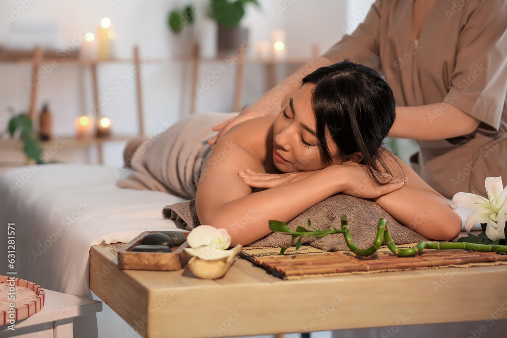 Pretty young Asian woman having massage in spa salon