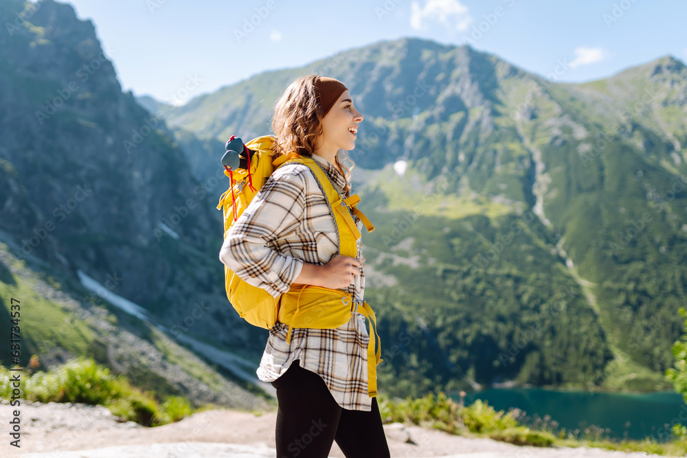 Young beautiful tourist woman with curly hair on top of a mountain. Active woman enjoys the beautifu