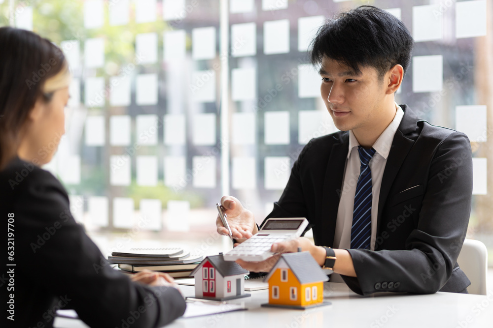 Businessman, real estate agent holding a calculator, presenting a price quote to a client for a hous