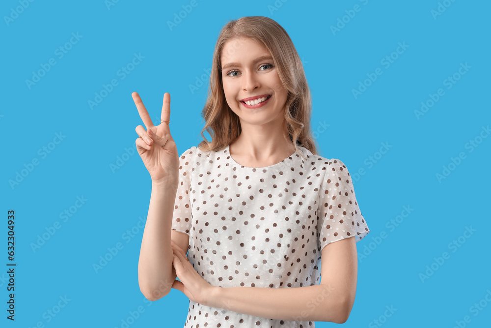 Young woman showing two fingers on blue background