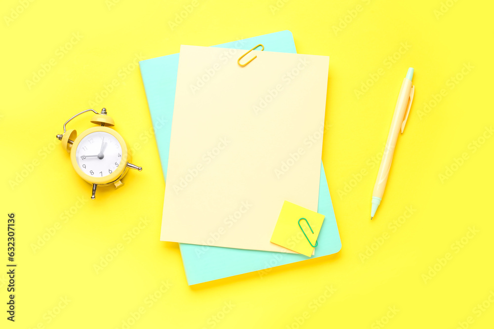 Paper sheets and clock on yellow background