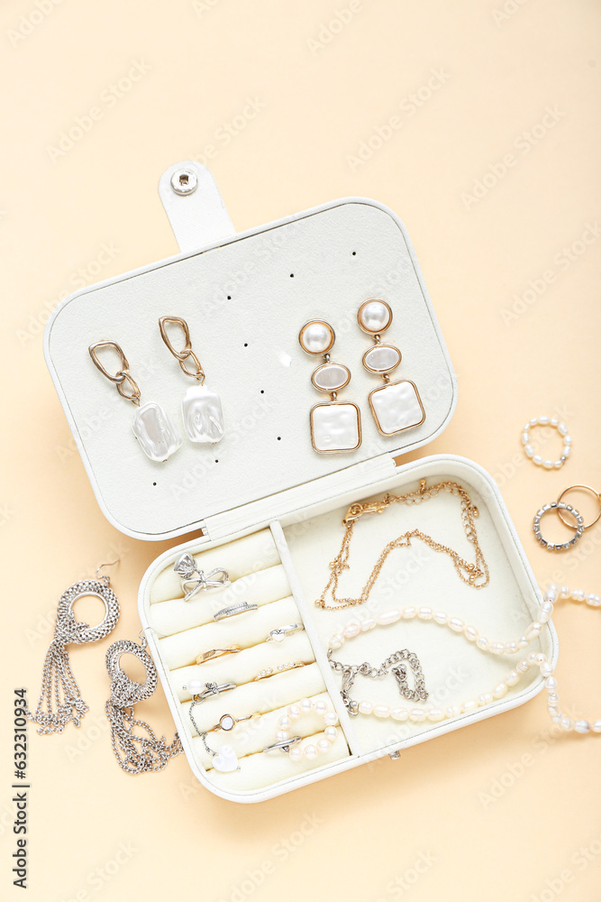 Organizer with stylish jewelry on pale orange background