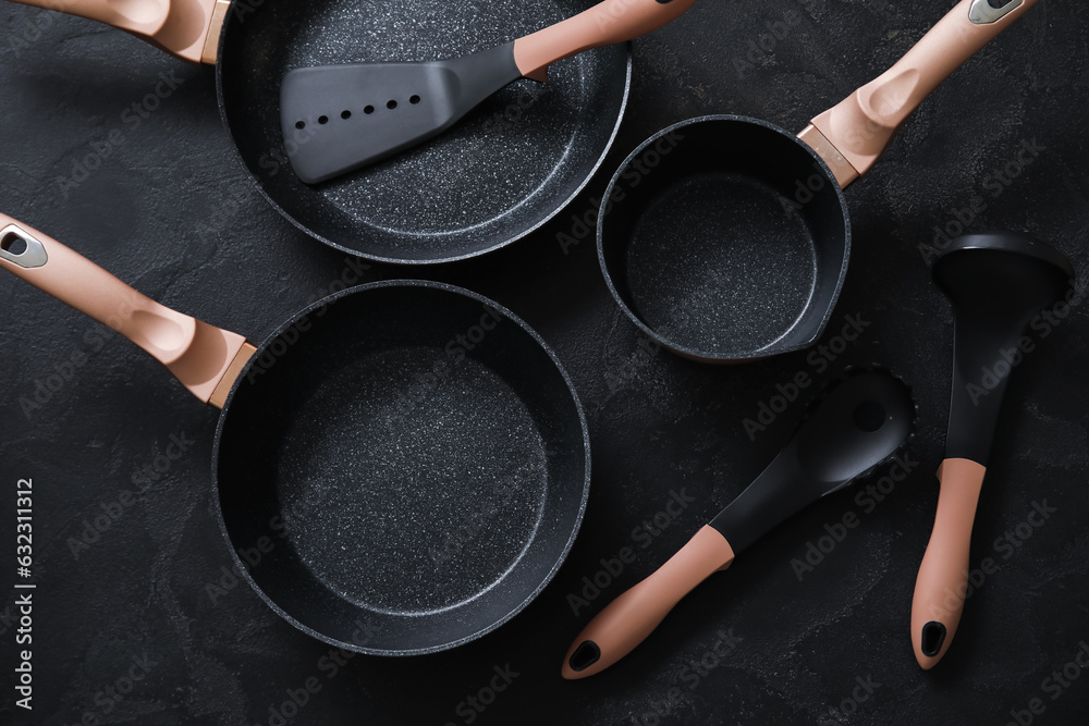 Set of cooking pots and kitchen utensils on dark background