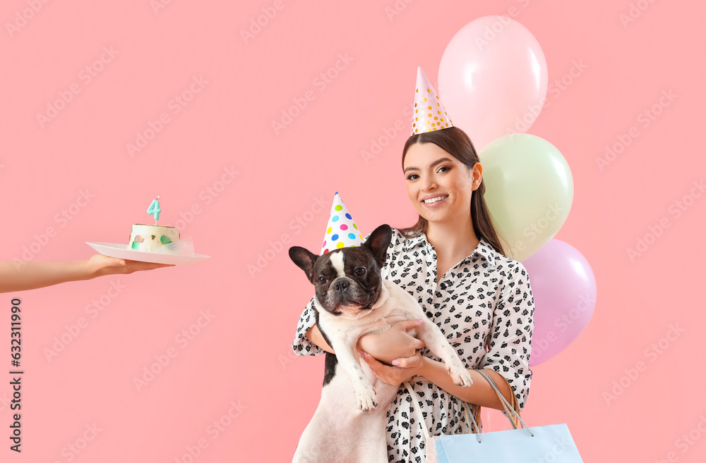 Young woman with her French bulldog celebrating Birthday on pink background