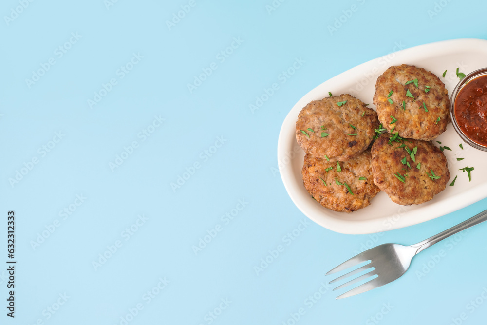 Cutlets with chopped parsley, ketchup and fork on blue background