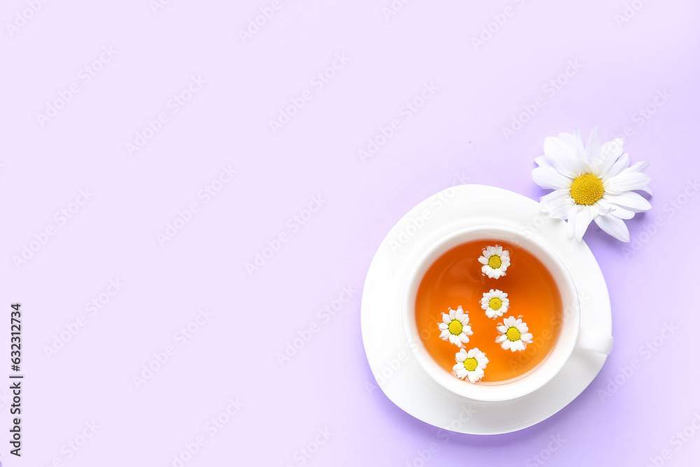 Cup of natural chamomile tea with flower on lilac background