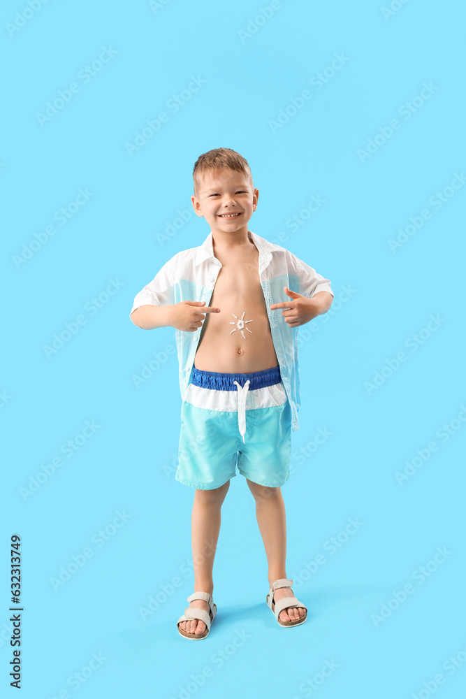 Happy little boy with sunscreen cream on his body against blue background