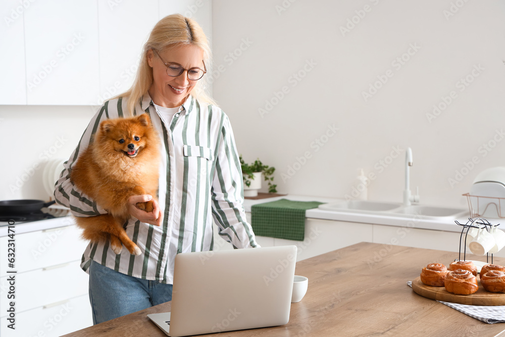 Mature woman with Pomeranian dog and cup of coffee in kitchen