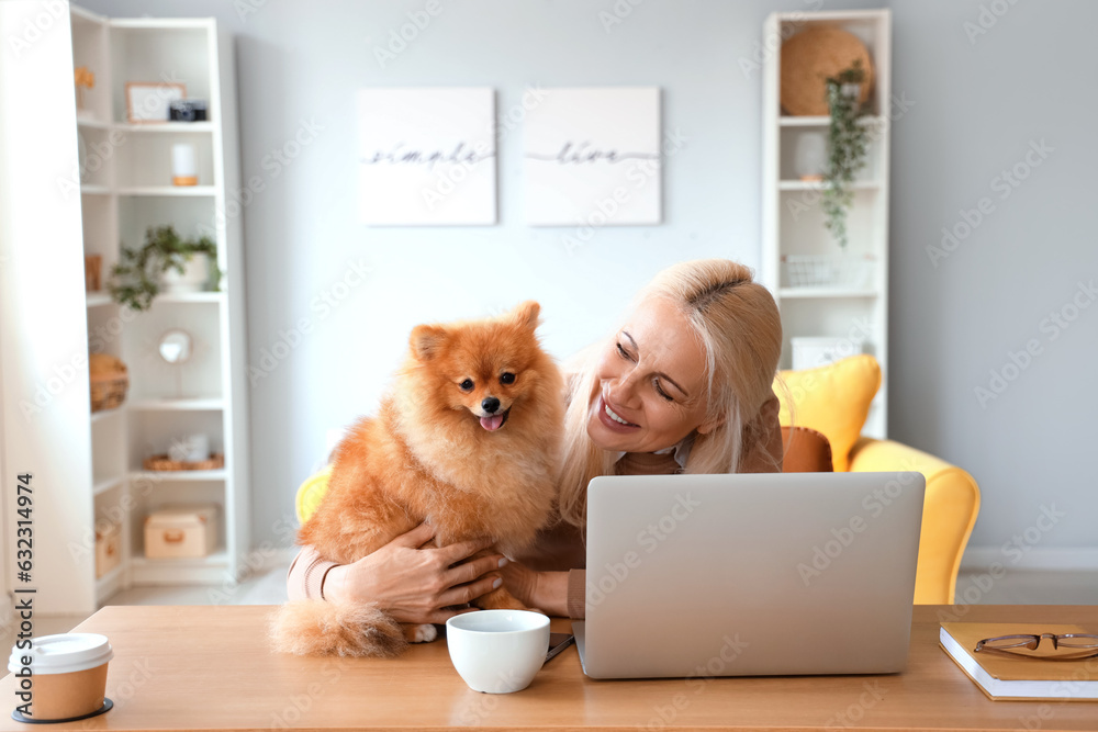 Mature woman with Pomeranian dog at table in office