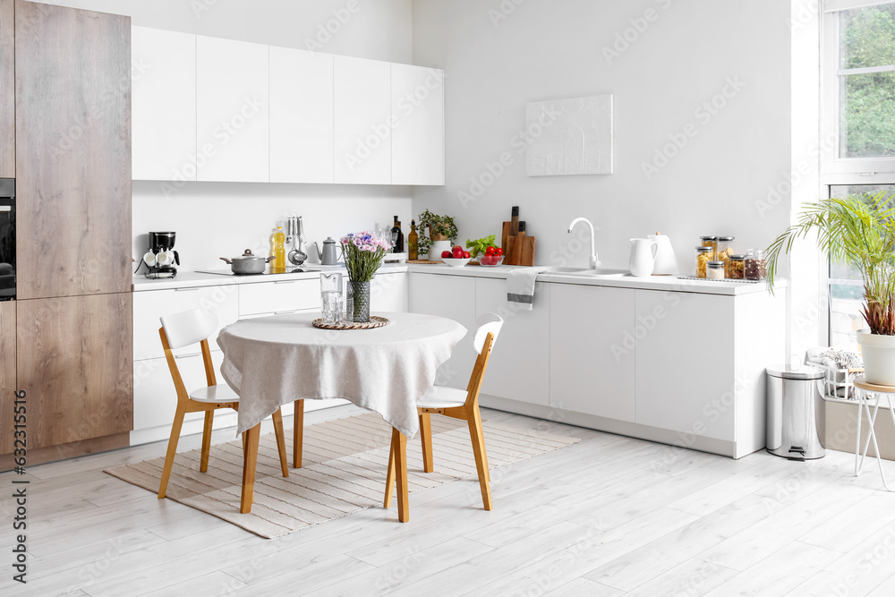 Interior of modern kitchen with flowers on dining table