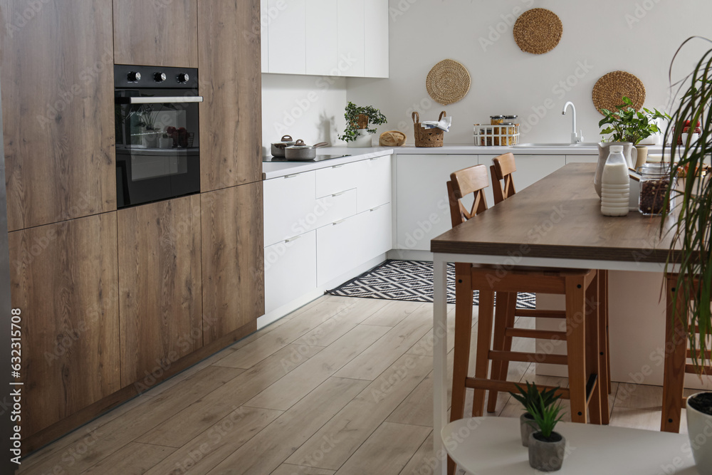 Interior of light kitchen with white counters, island and integrated oven