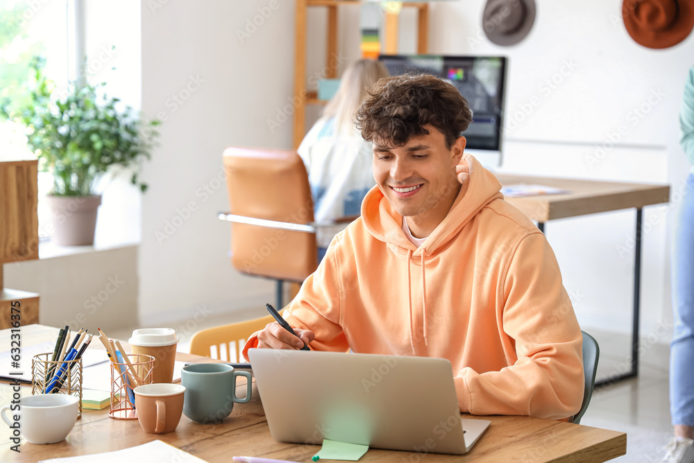 Male graphic designer working with laptop at table in office