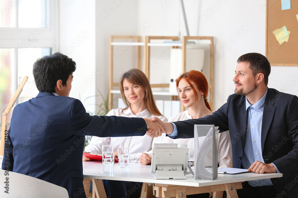 Human resources manager shaking hands with male applicant in office