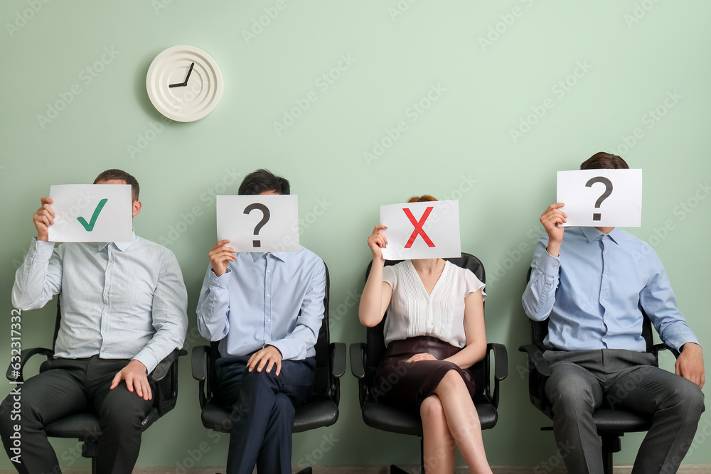 Young applicants holding paper sheets with different marks in room