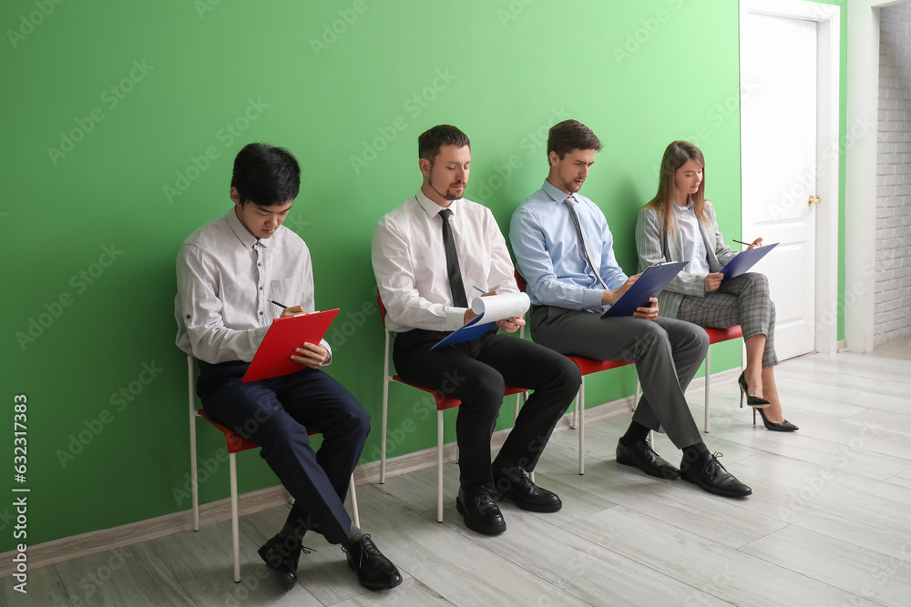 Young applicants with clipboards waiting for job interview in room