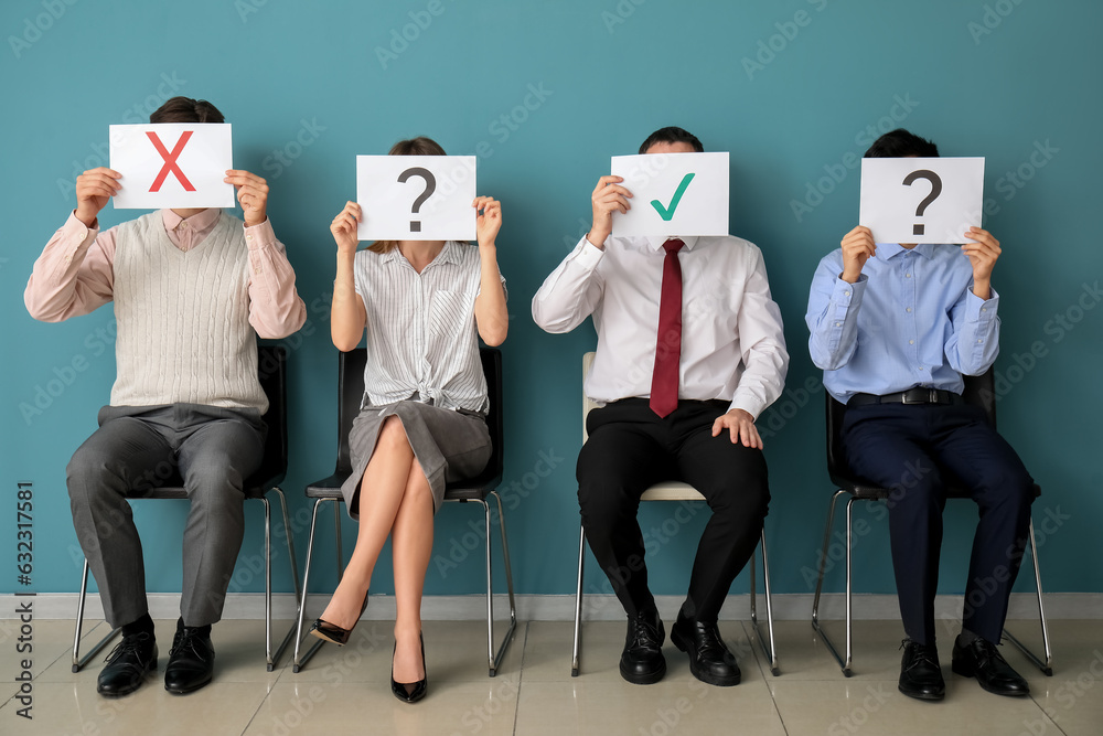 Young applicants holding paper sheets with different marks in room