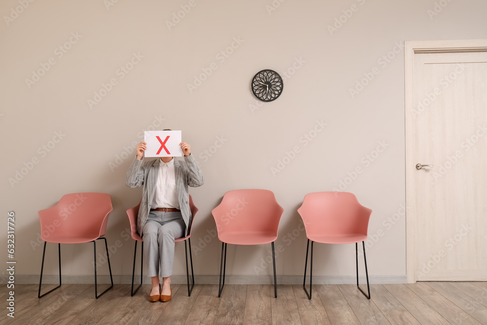 Female applicant holding paper sheet with cross in room