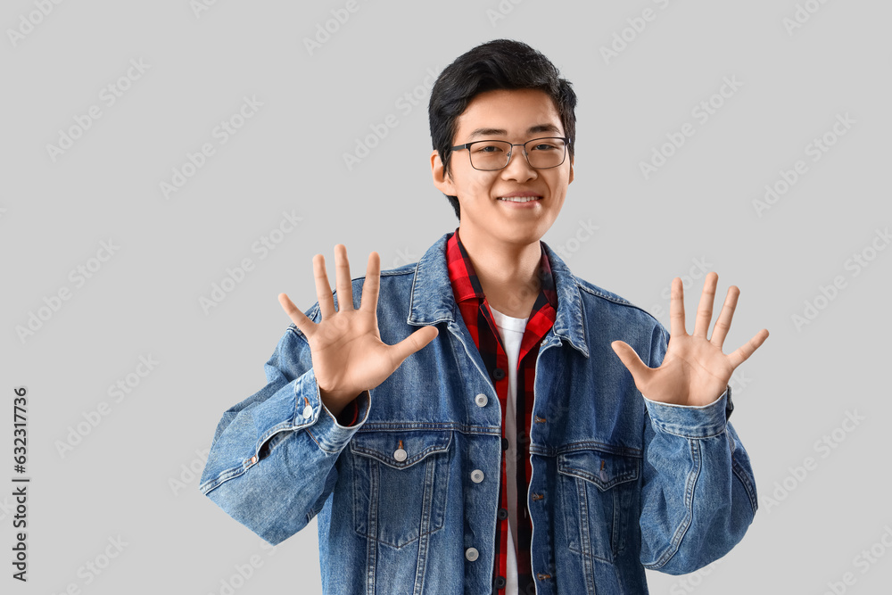 Young Asian man showing ten fingers on light background