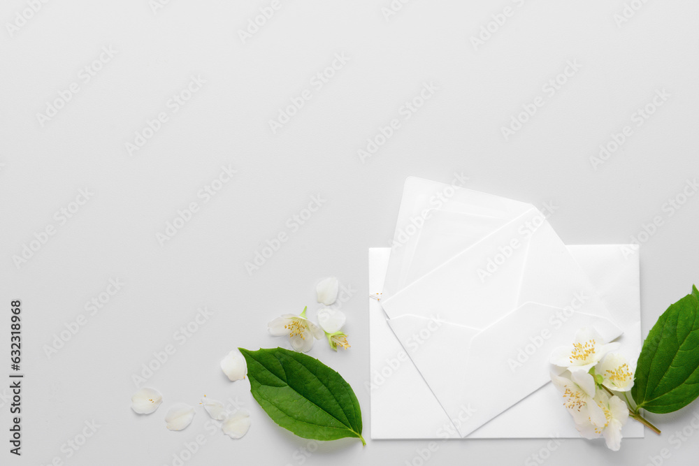 Composition with envelopes and beautiful jasmine flowers on light background