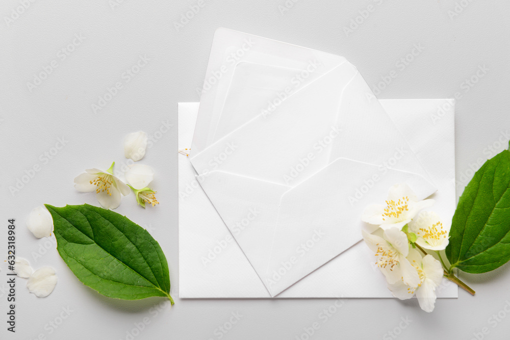 Composition with envelopes and beautiful jasmine flowers on light background