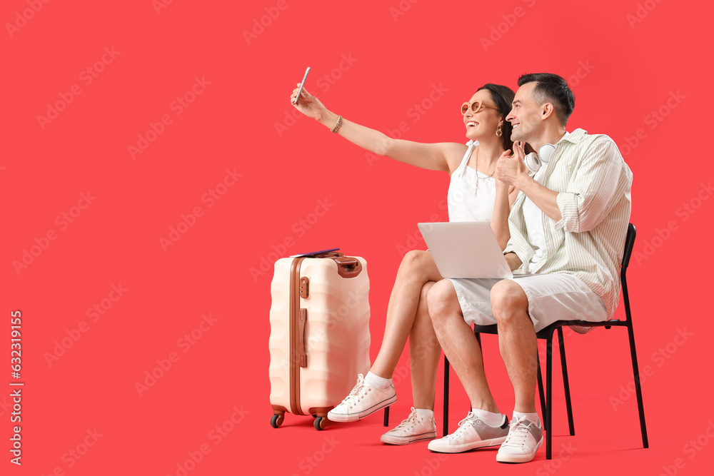 Young couple with gadgets taking selfie on red background