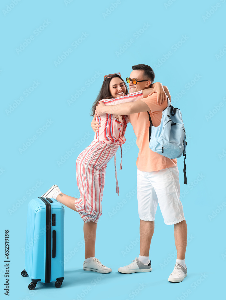 Young couple with bags hugging on blue background