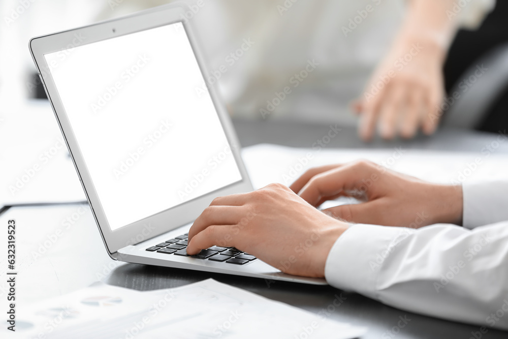 Male business consultant working with laptop at table in office, closeup