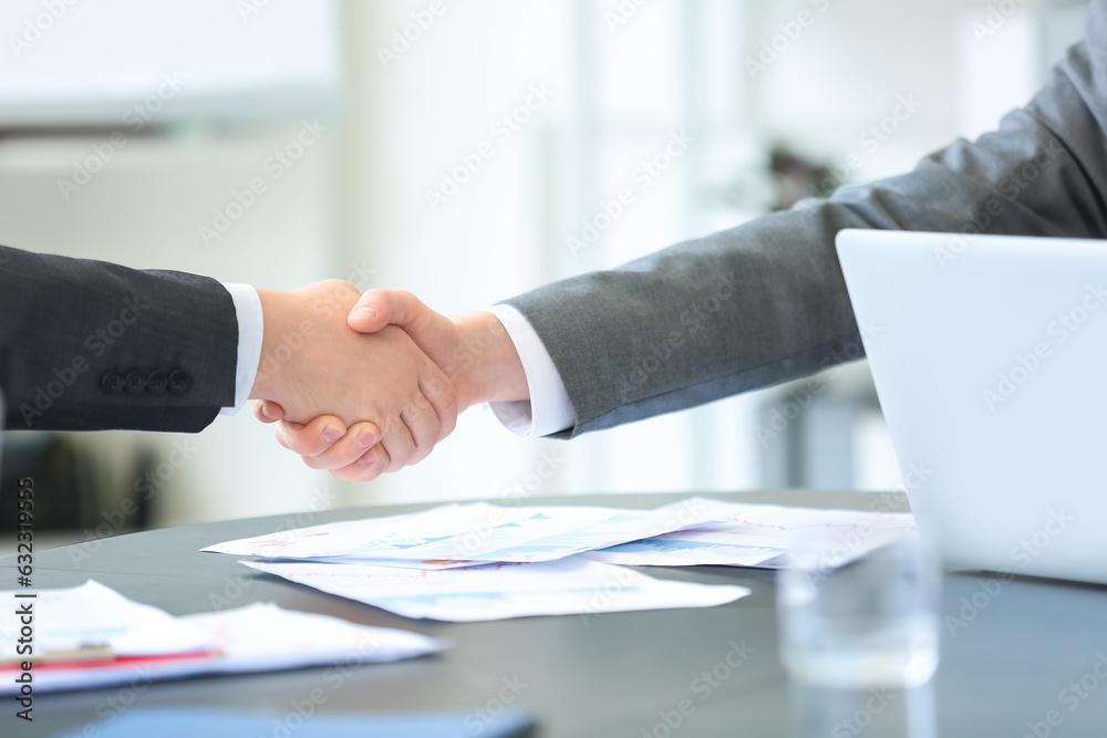 Male business consultants shaking hands in office, closeup