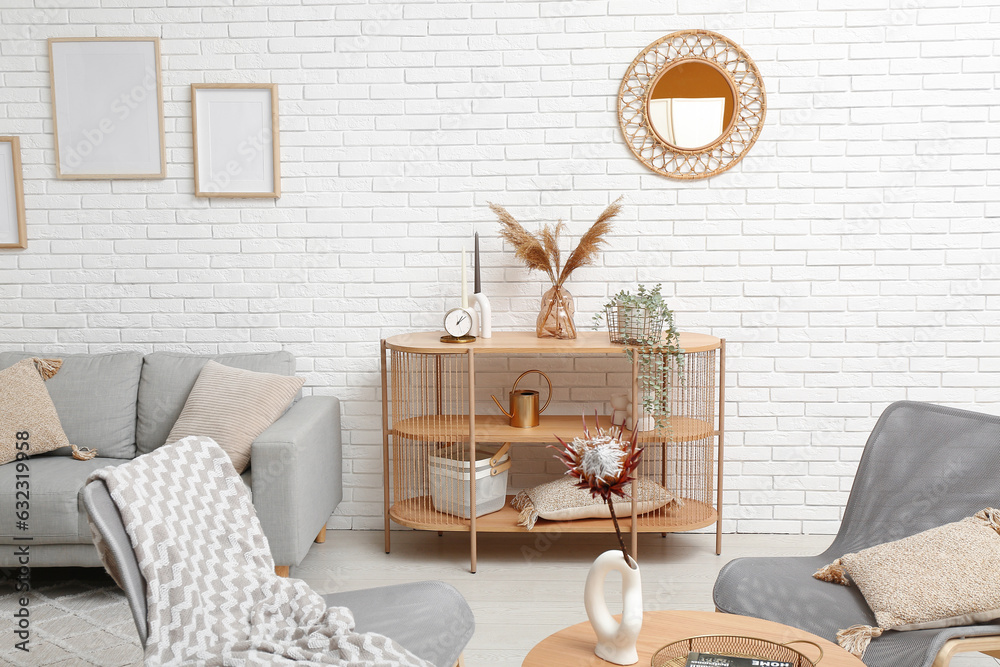 Modern living room interior with shelving unit, grey sofa and armchairs