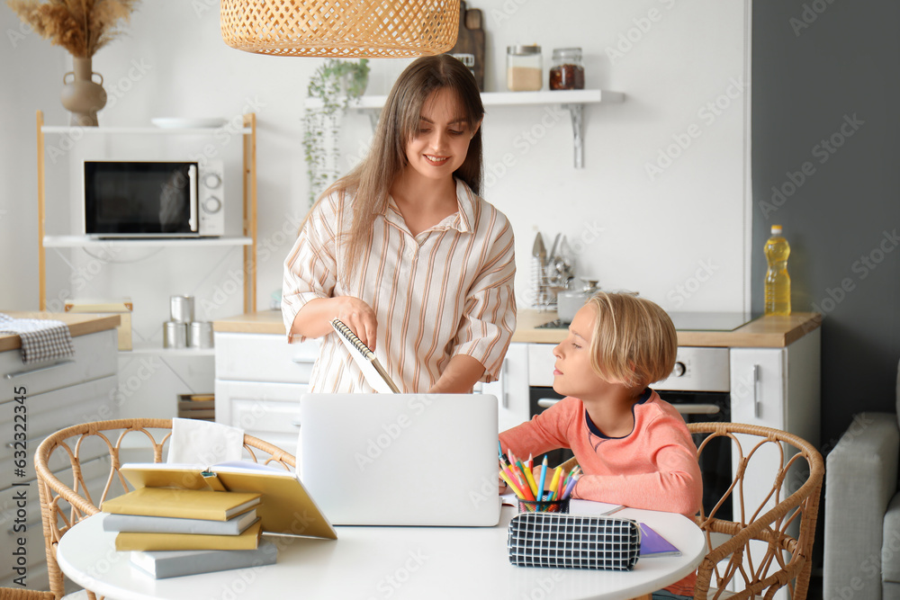 Little boy doing homework with his mother in kitchen