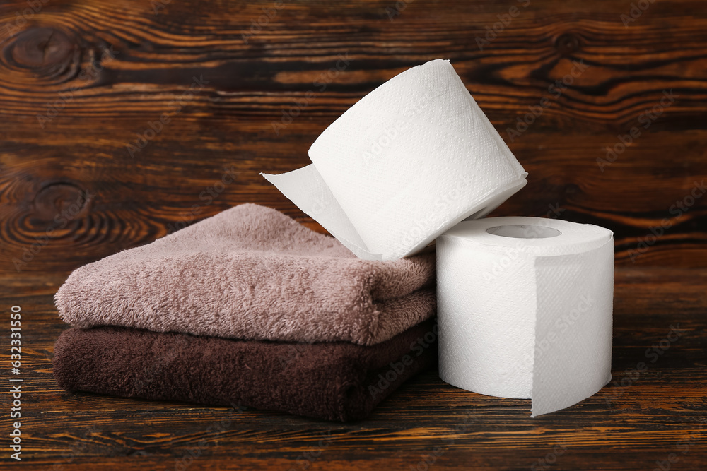 Rolls of toilet paper and towels on wooden background