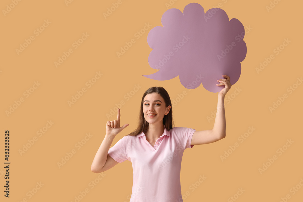 Beautiful happy young woman with speech bubble pointing at something on orange background